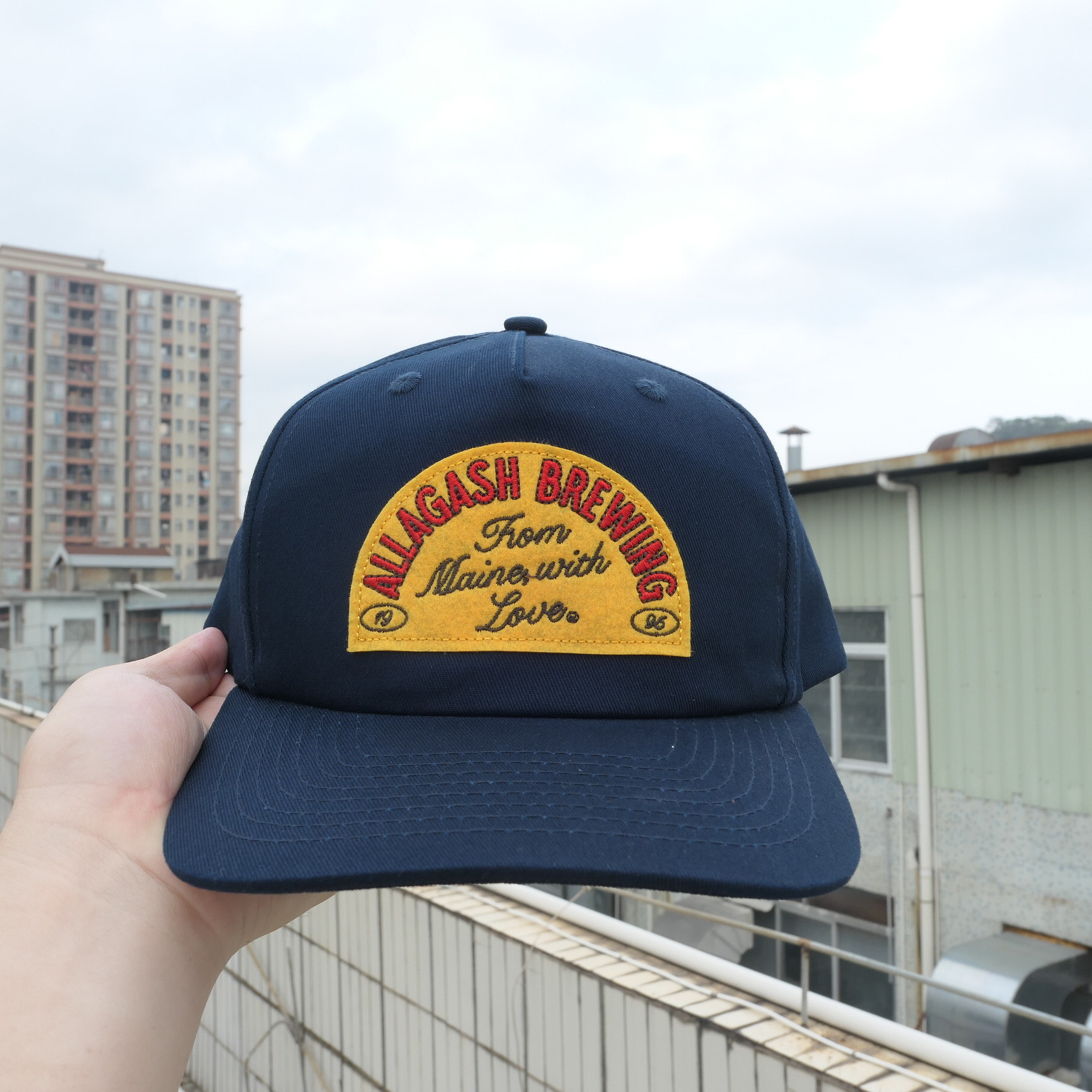 Navy Allagash cap with a yellow and red patch