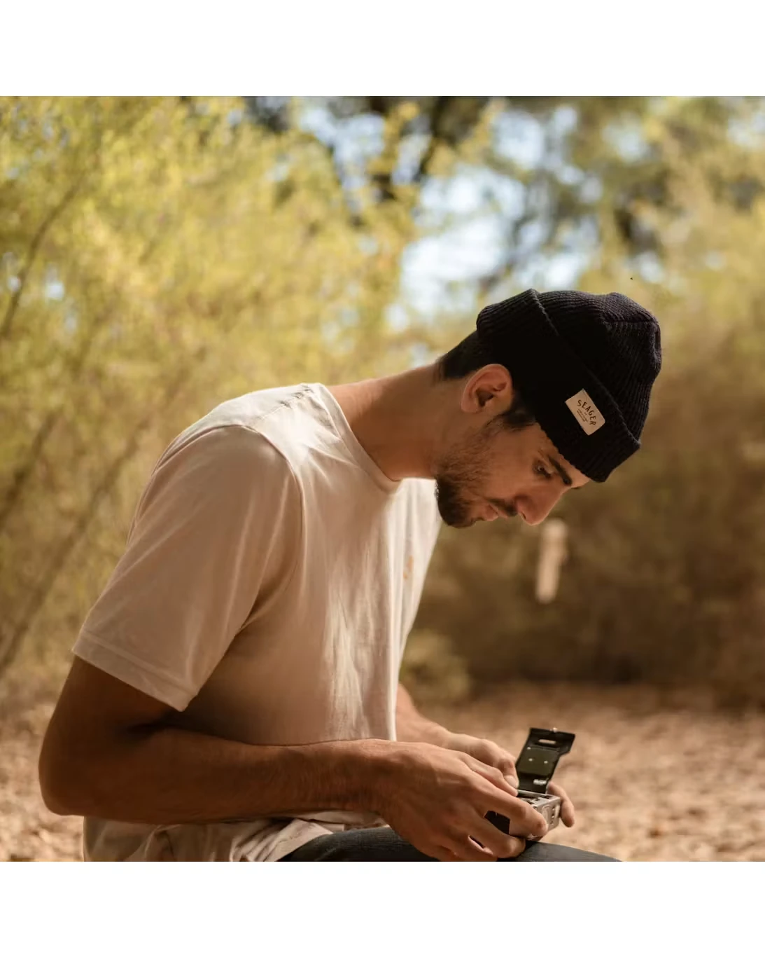 Black Seager cuffed beanie worn outdoors while checking a film camera