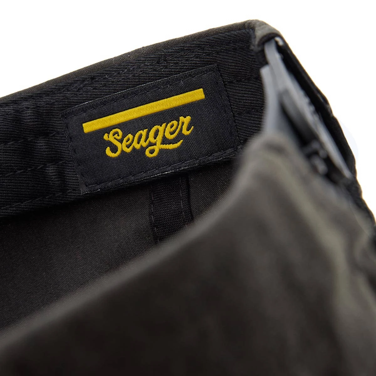 Yellow Seager woven label sewn onto the black interior sweatband of a cap