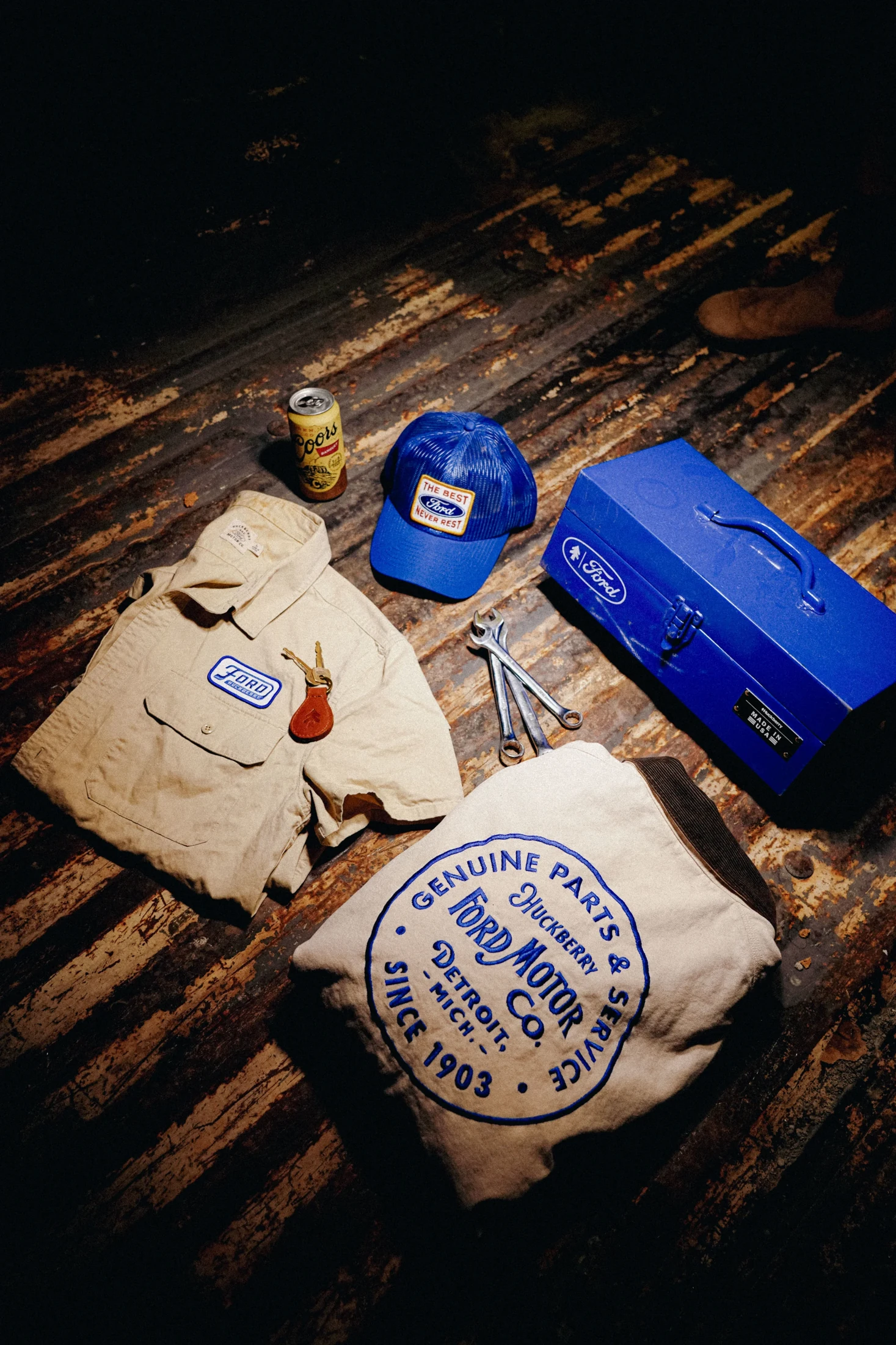 A Ford and Huckberry collection arranged together: embroidered headwear, a work shirt, a jacket and a blue toolbox