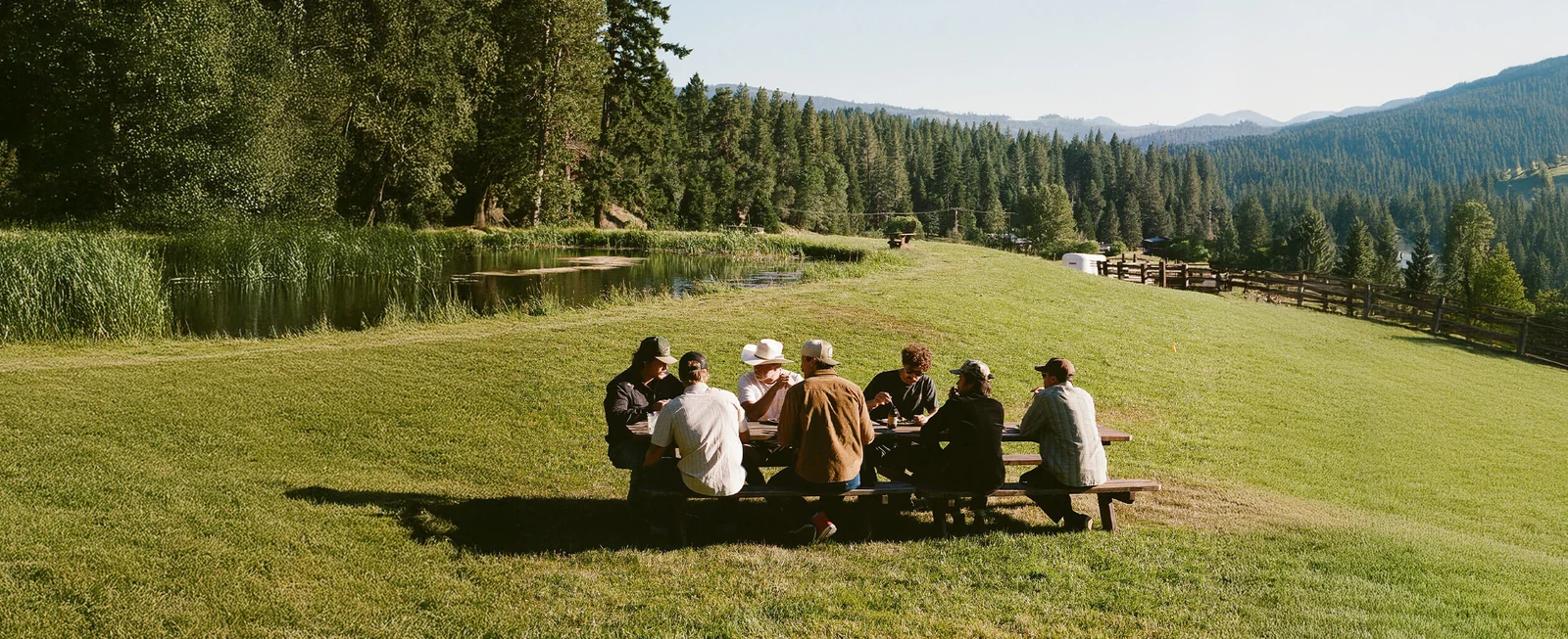 A group gathered around a picnic table beside a mountain lake in Seager’s Fall 2026 campaign